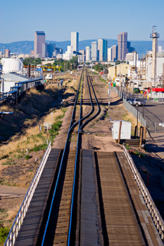 View of railroad track heading towards skyline of Denver.