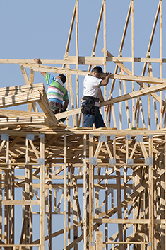 Two mean on top of the framework of a new house construction.